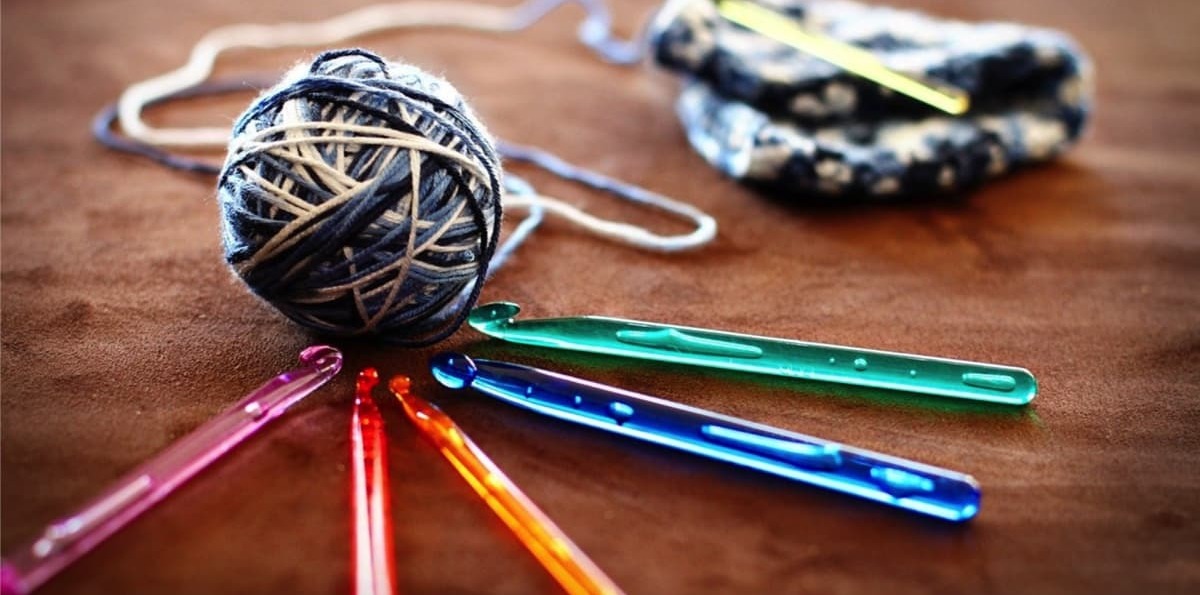 weaving together good communications illustrated by colourful crochet hooks and wool