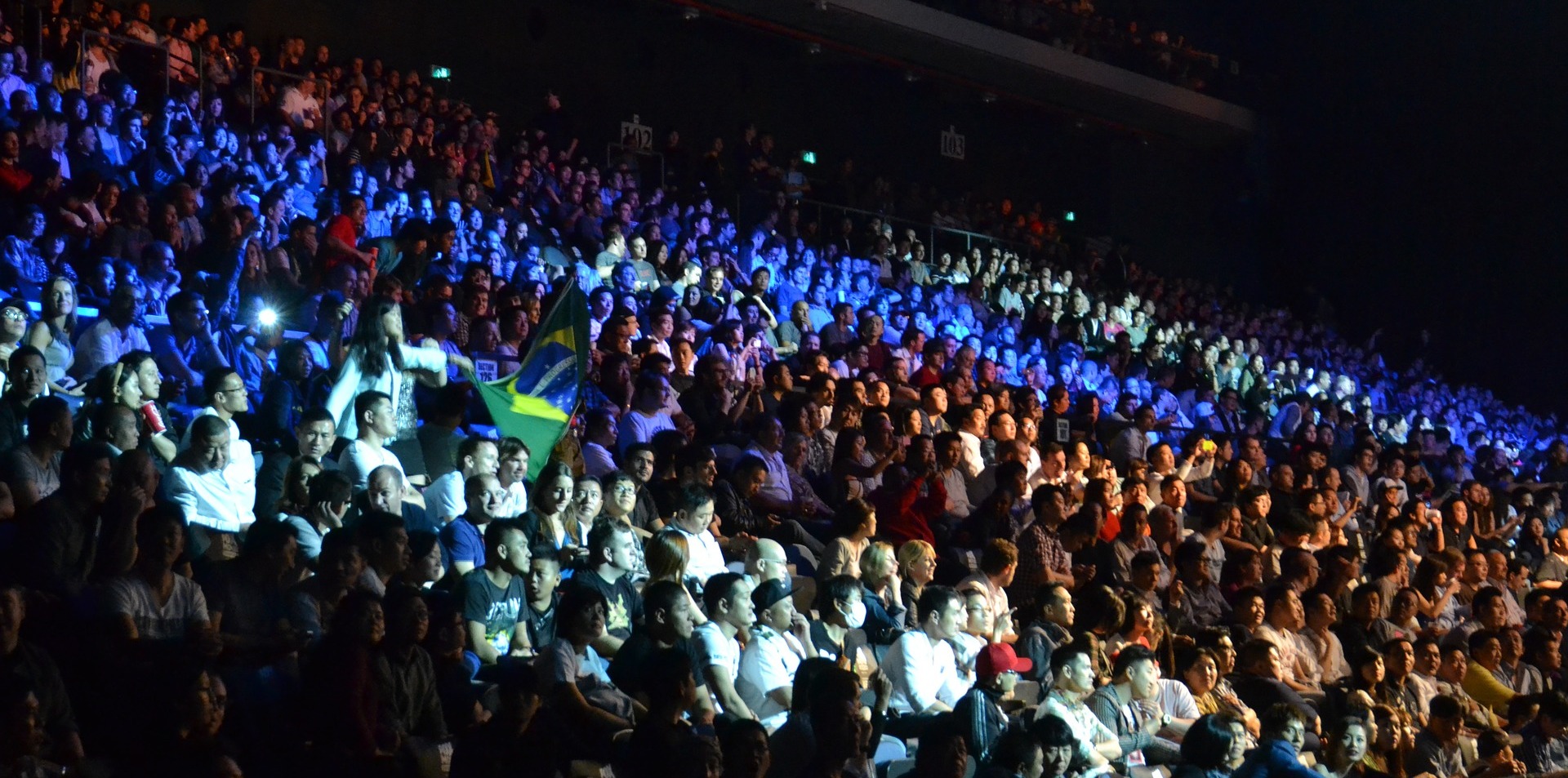 Many people in an audience with blue and white lighting